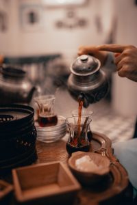 Traditional Persian tea being poured from a metal teapot into a glass