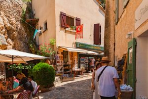 Tourists exploring a charming cobblestone street with shops and outdoor cafés